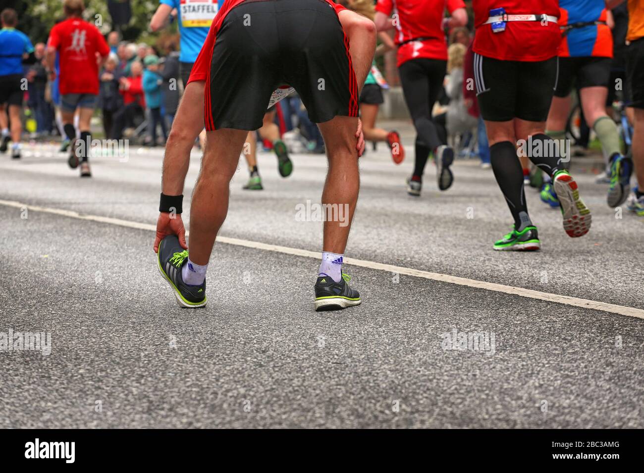 Runner at Hamburg marathon is stretching his leg Stock Photo