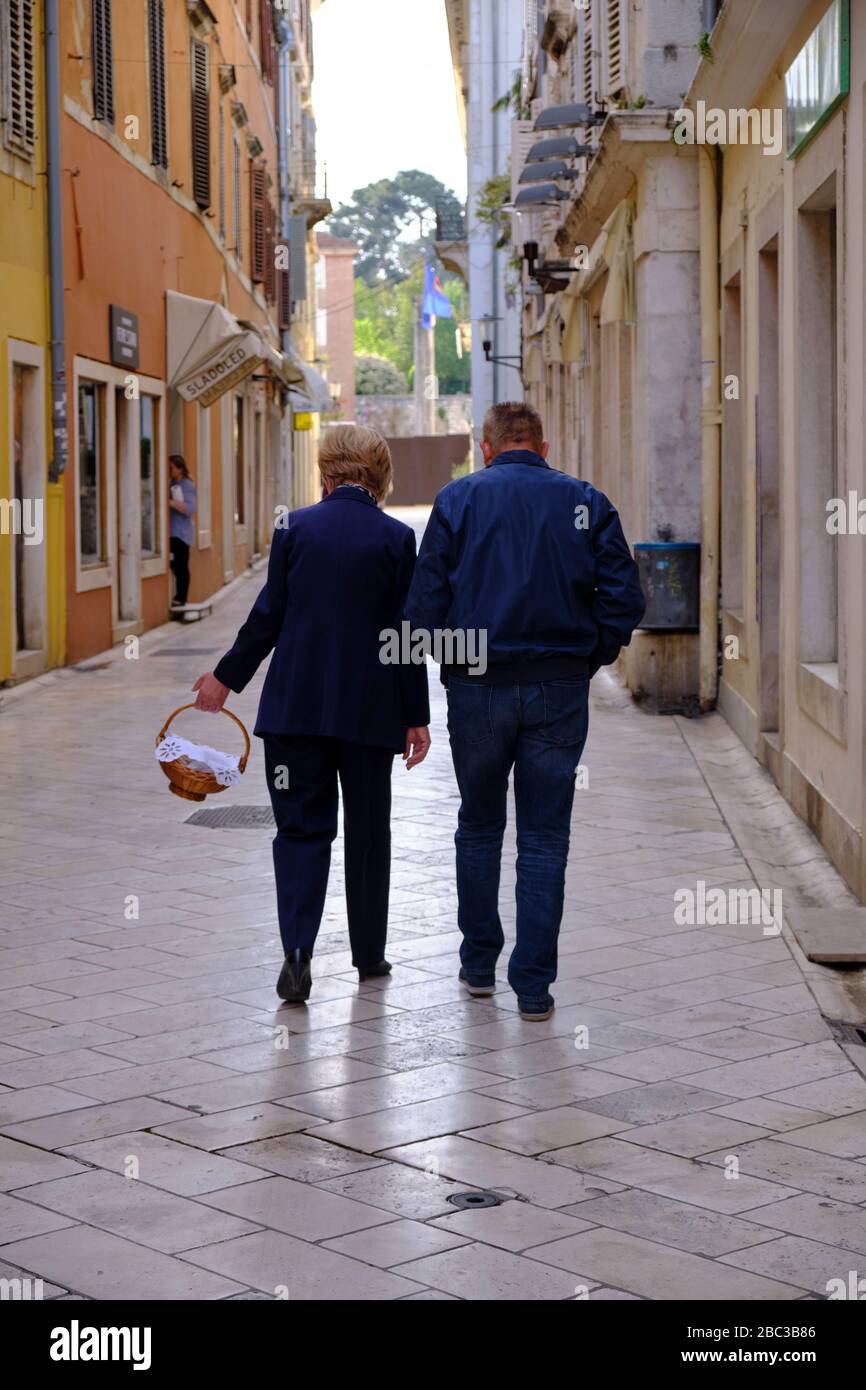 Older couple walking away on their way to Easter Mass in Zadar, Croatia, Stock Photo