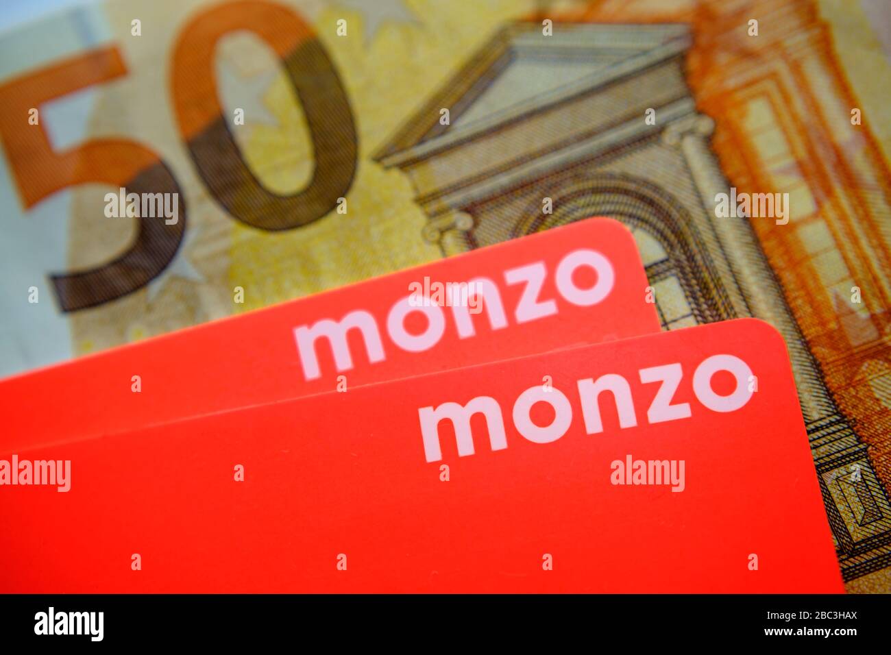 Monzo bank card placed on top of 50 euro bank notes. Close up photo. Stock Photo