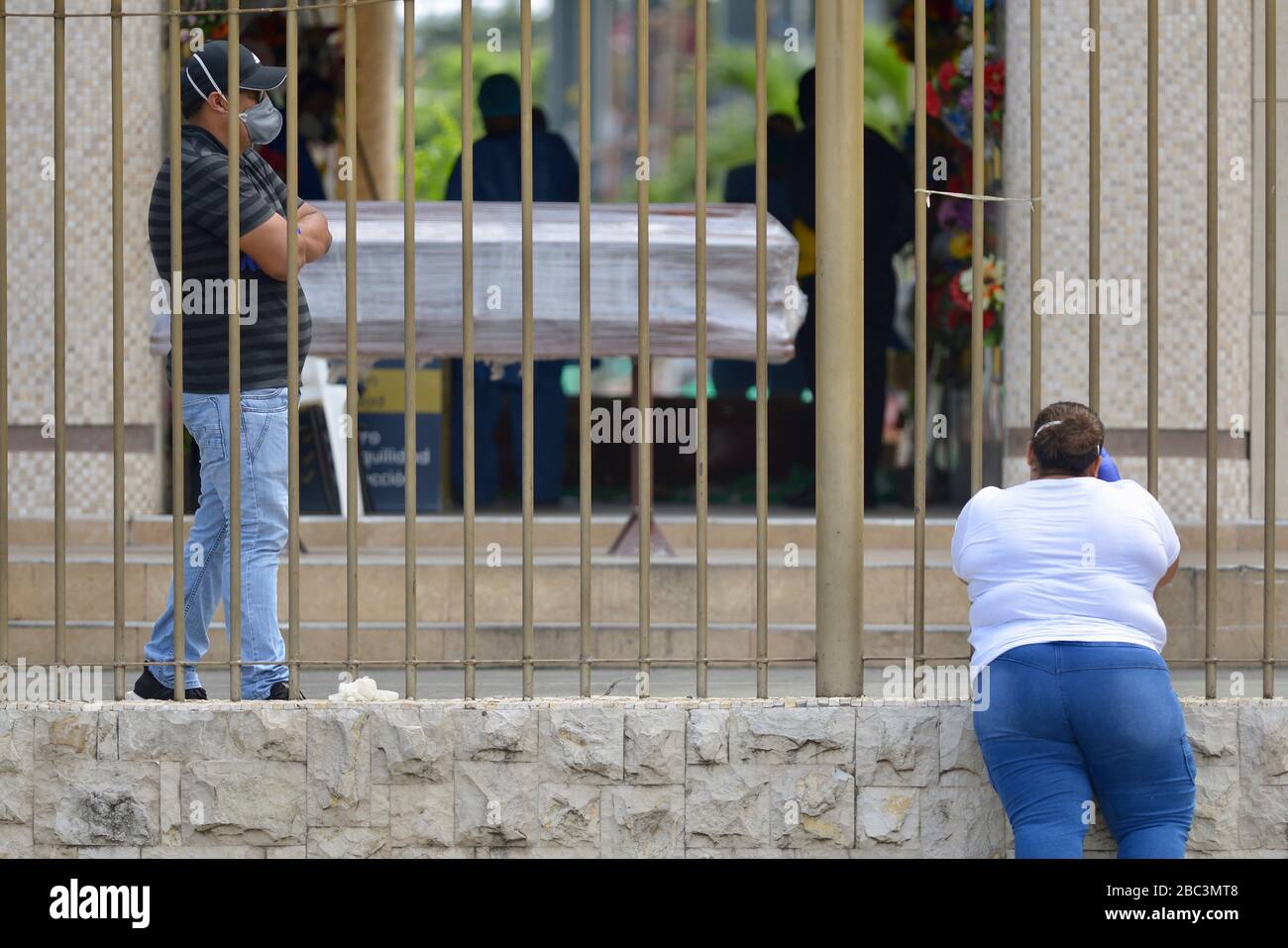Guayaquil, Ecuador. 02nd Apr, 2020. People wait next to a coffin at the entrance of the cemetery 'Jardines de la Esperanza' (Gardens of Hope). The port city of Guayaquil is the most affected by Covid-19 in Ecuador. Dead bodies lie in the apartments for days, the morgues of the hospitals are overcrowded. The city administration requested four refrigerated containers in which the corpses can be temporarily stored. Credit: Marcos Pin Mendez/dpa/Alamy Live News Stock Photo