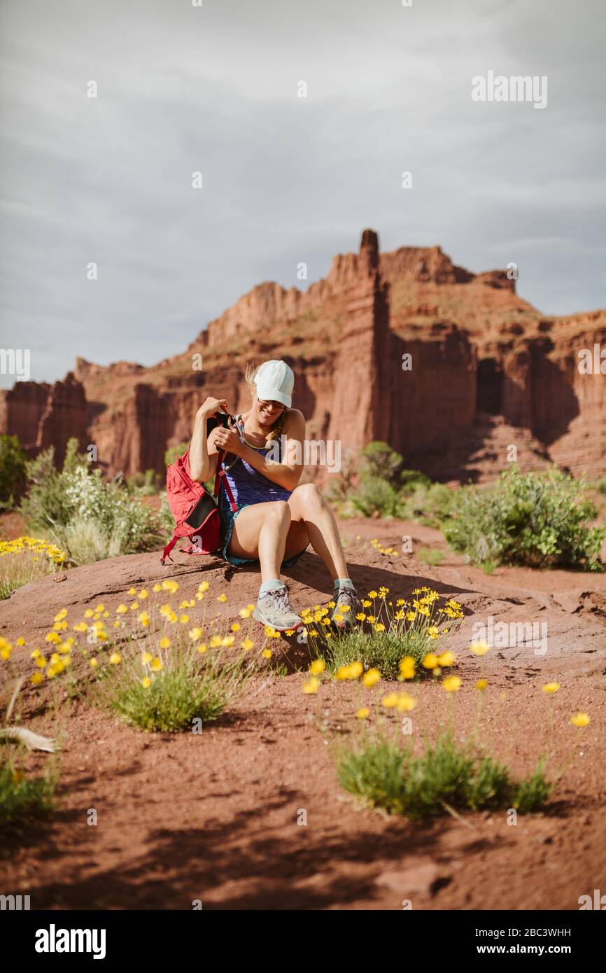 hiker takes off backpack to rest under red sandstone towers Stock Photo