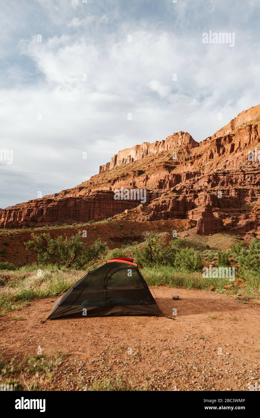 black tent without rain fly set up beneath red rocks near moab utah