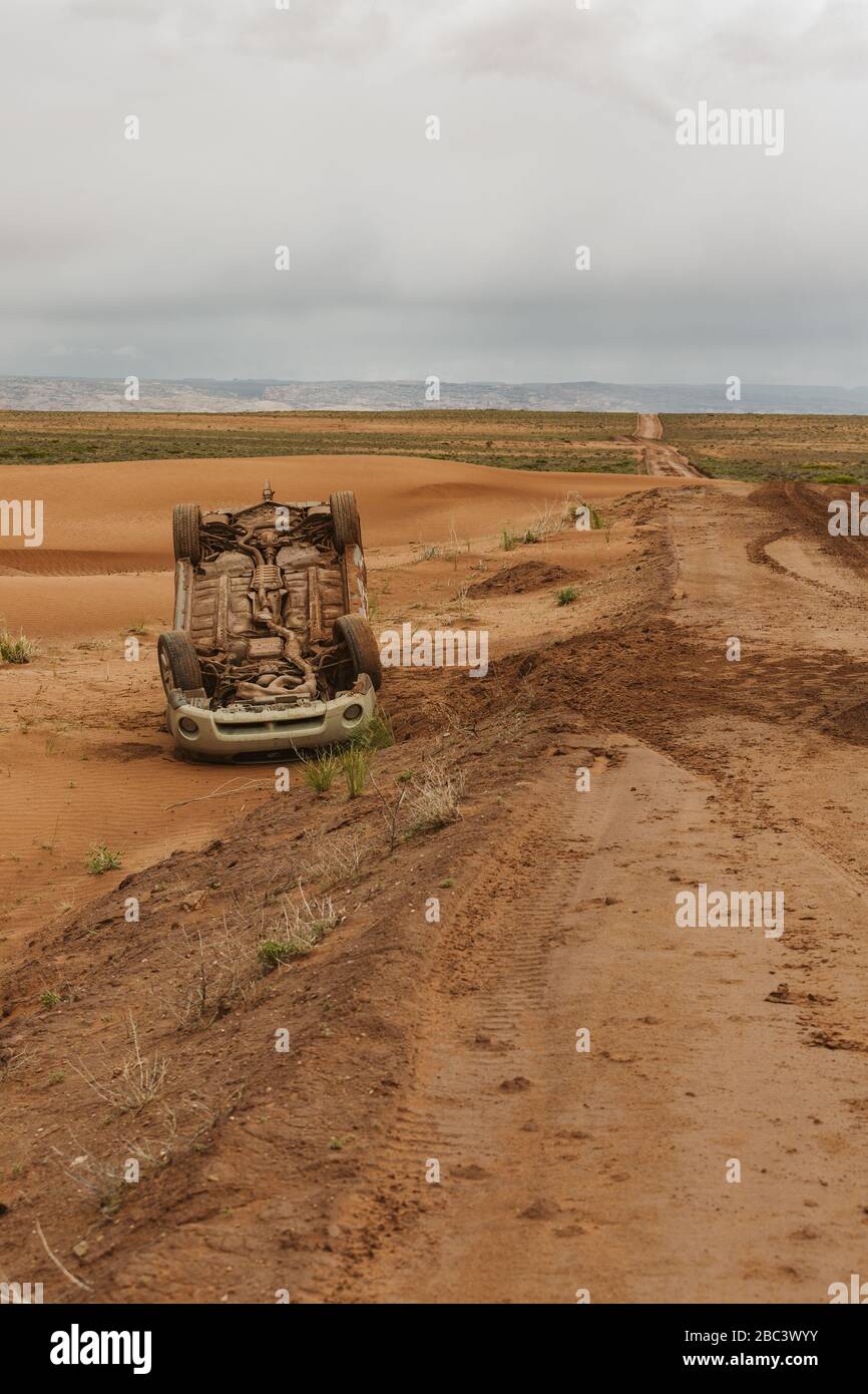 upside down car that has flipped on a muddy dirt road in utah desert Stock Photo