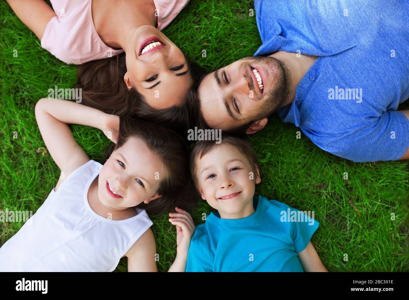 Young Family Lying on the Grass in Park Stock Photo - Alamy