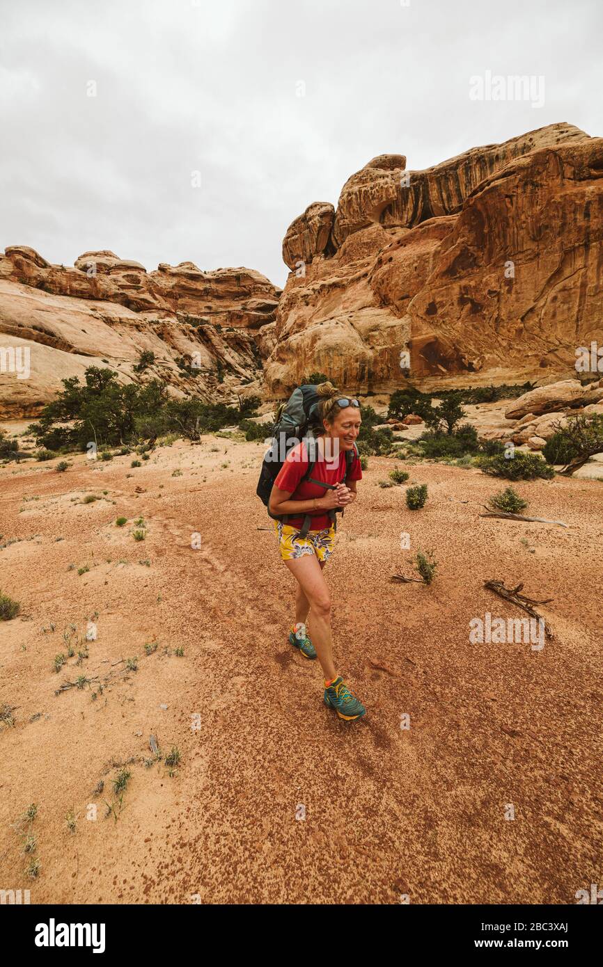 smiling female backpacker walks through canyon floor near moab utah Stock Photo