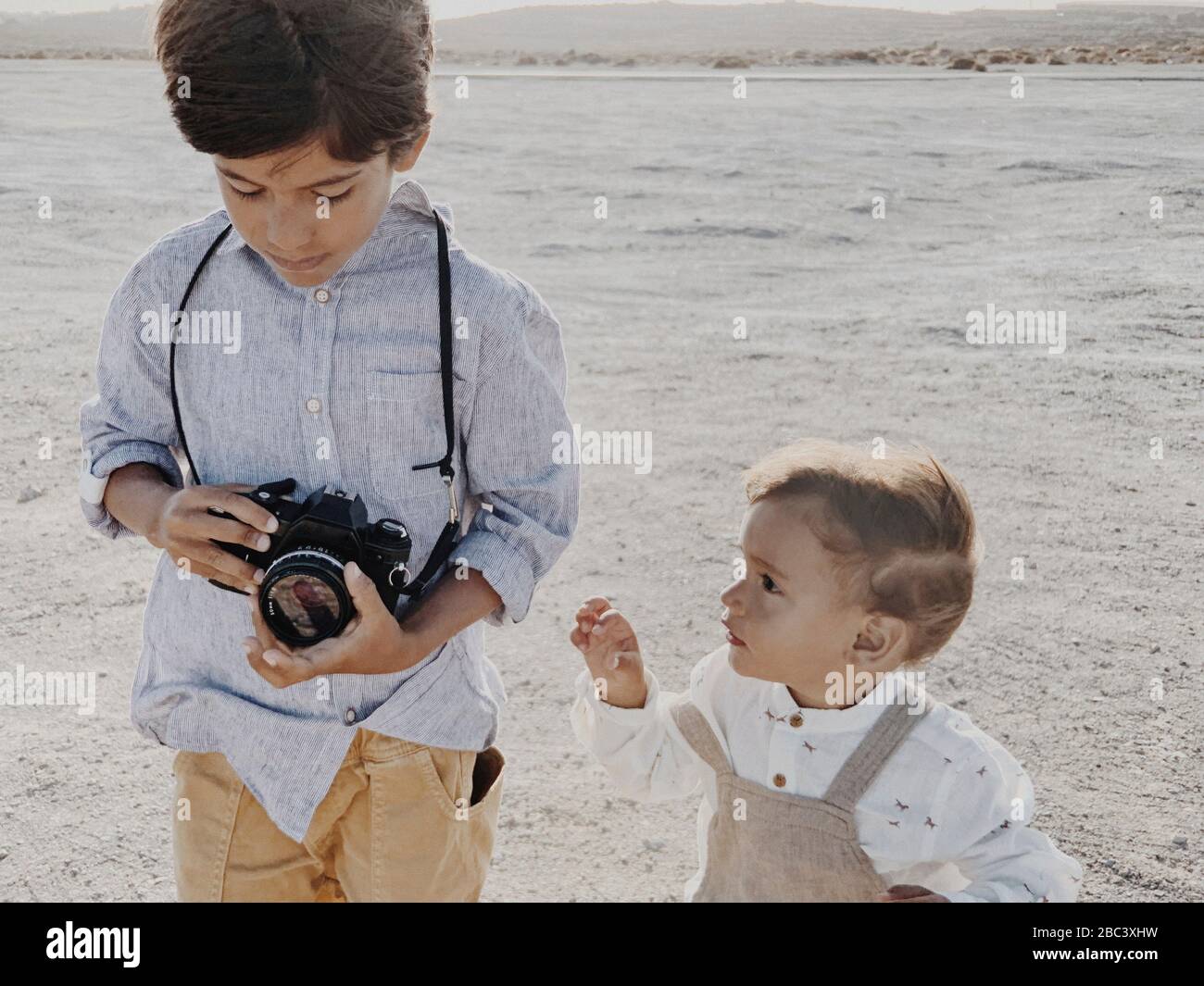 A kid holds a camera and a younger kid stands next to  me Stock Photo