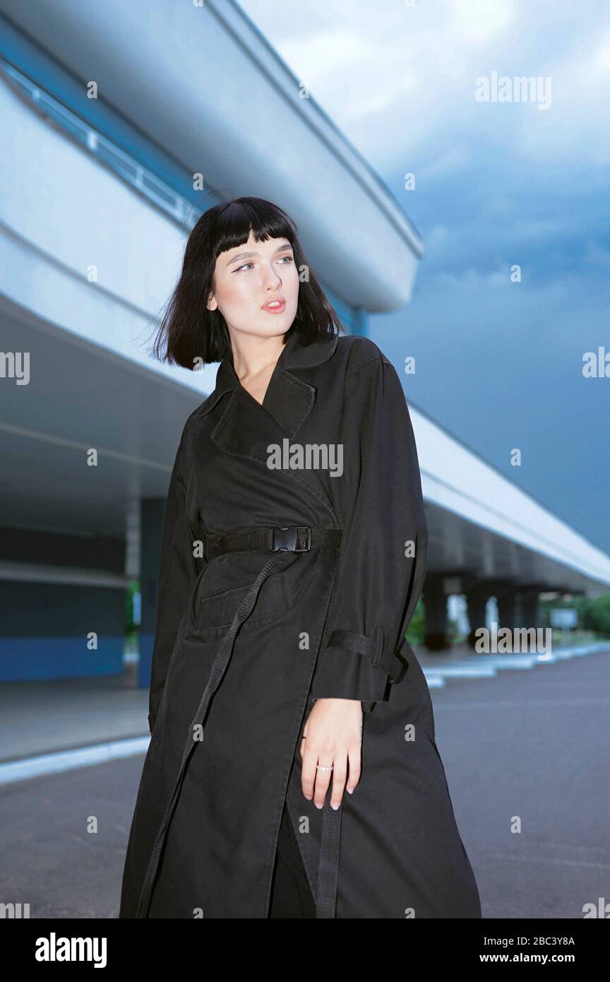 Woman in a black long coat at the train station Stock Photo