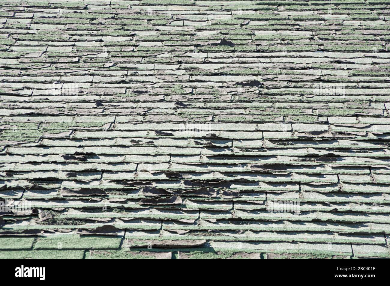 sun damaged old roof with peeling and curling composition shingles Stock Photo