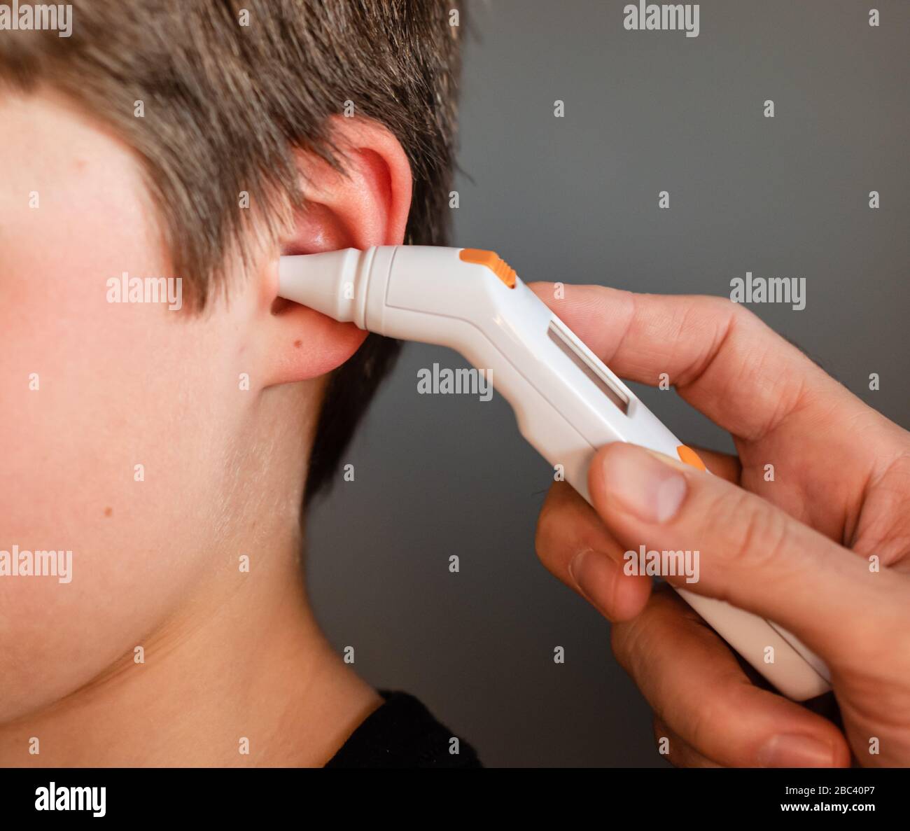 Close up of child getting temperature taken with an ear thermometer. Stock Photo