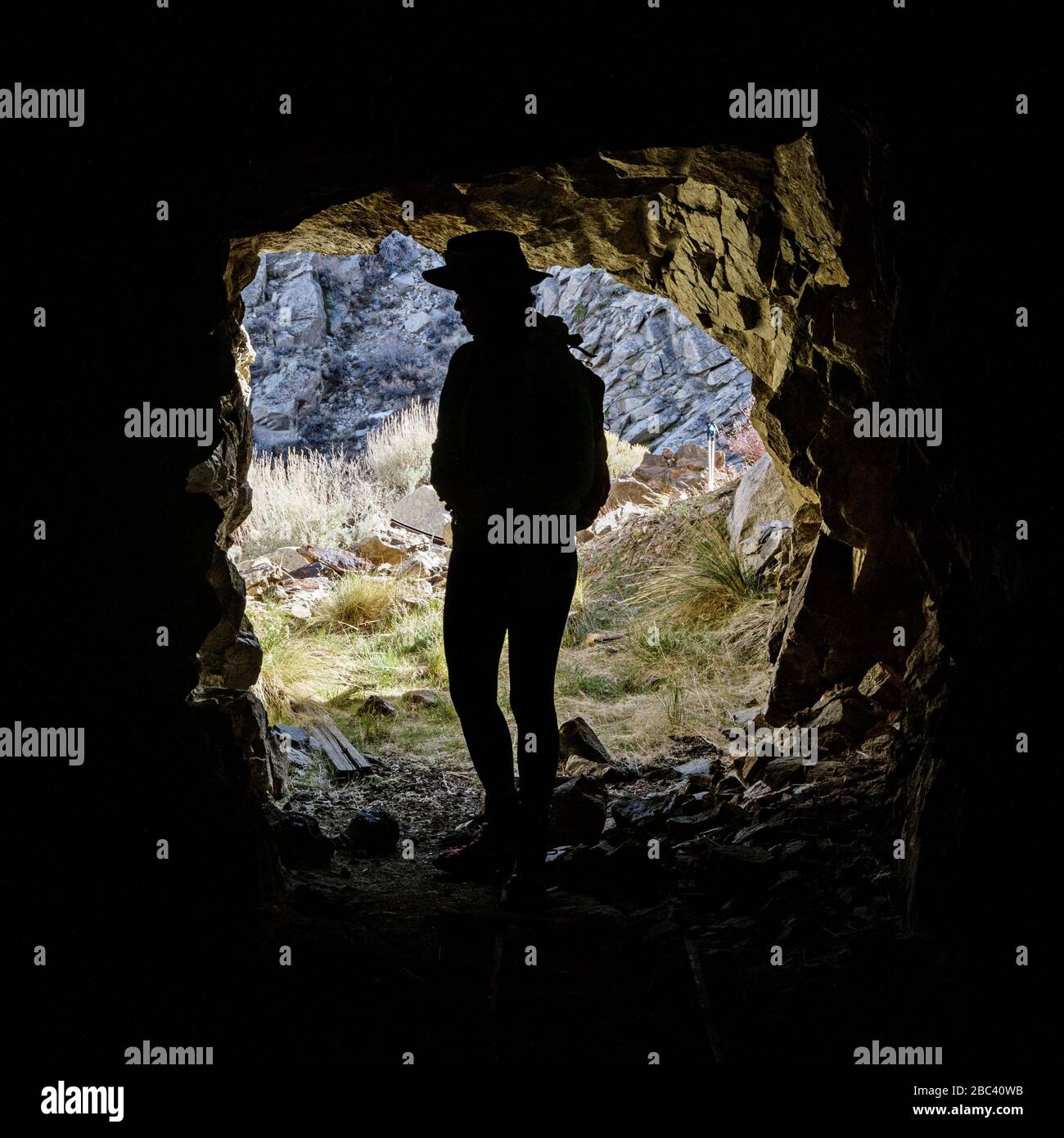 silhouette of woman standing in an old mine entrance from inside the mine Stock Photo