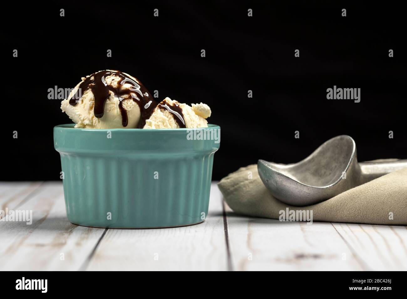Scoops of vanilla ice cream in a bowl smothered with chocolate syrup. Stock Photo