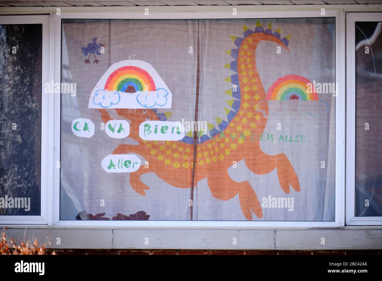 House window with rainbow drawings and slogan 'Ca va bien Aller' as message of hope in Montreal part of 'It's going to be OK' movement during CoVID19 Stock Photo