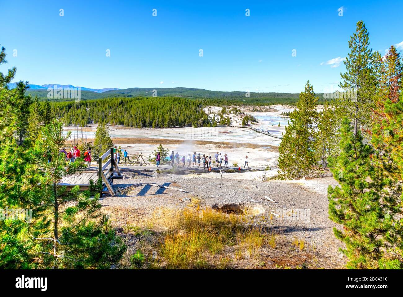 Unrecognizable visitors walking on the Porcelain Basin boardwalk trail surrounded by geothermal pools inside Norris Geyser Basin of Yellowstone Nation Stock Photo