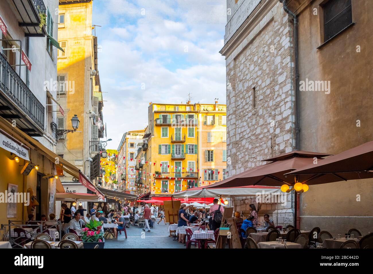 A lively afternoon at the Place Rossetti as tourists enjoy the cafes and shops in the colorful Vieux Old Town of Nice, France on the French Riviera. Stock Photo