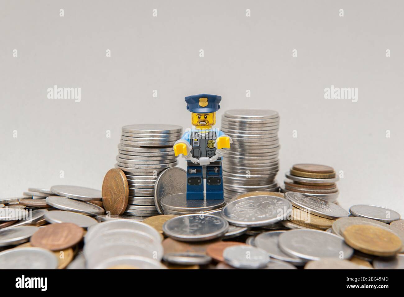 Florianopolis, Brazil, March 28, 2020: Policeman in uniform handcuffed by corruption near coins. Hand cuffed police officer for crime committed. Lego Stock Photo