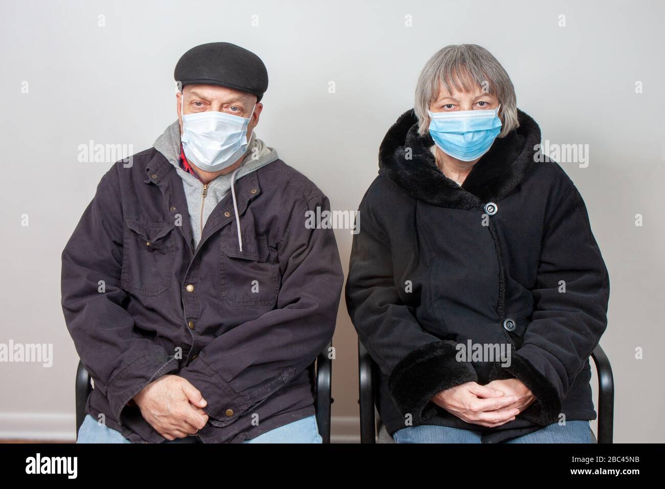 Senior Citizen Couple Wearing Face Masks In Waiting Room Stock Photo