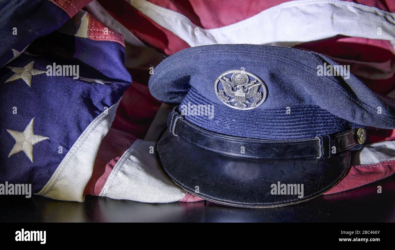 Close up, still life of military dress hat with American flag draped around it. Stock Photo