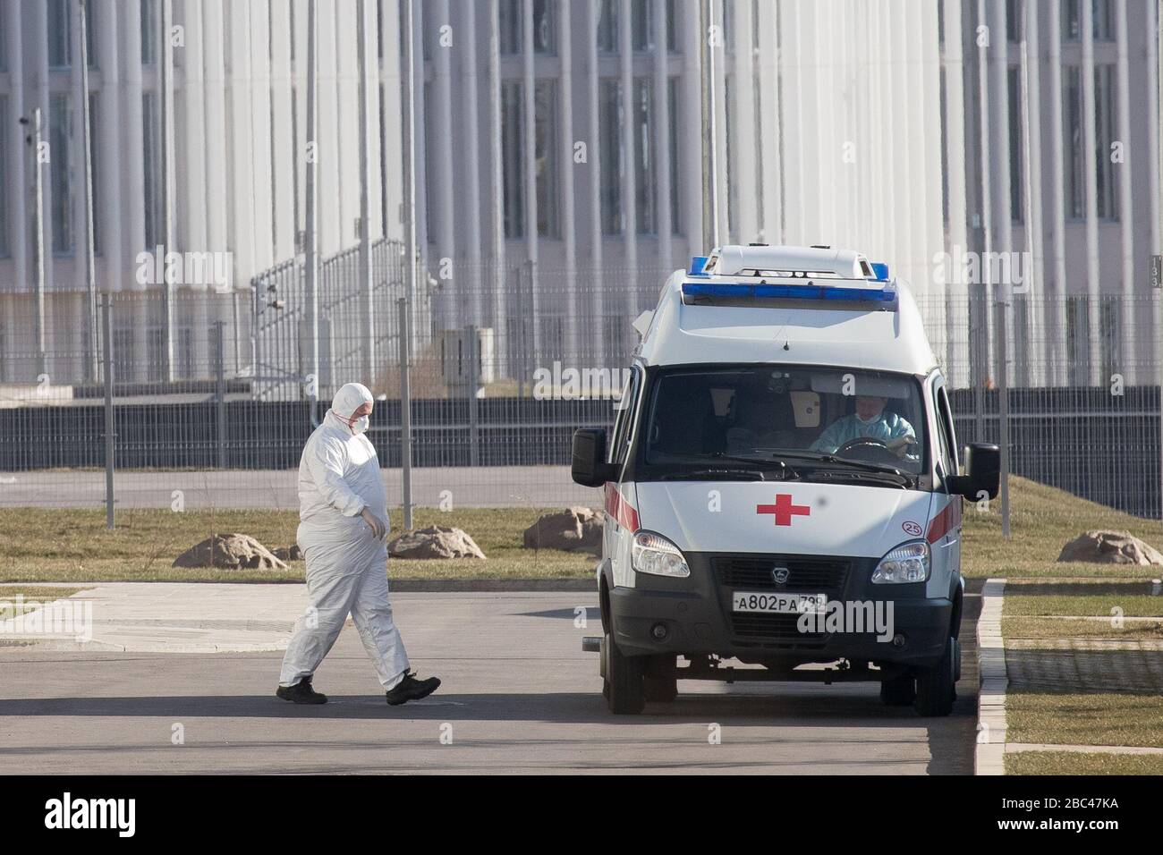 Moscow, Russia. 25th Mar, 2020. A medical specialist wearing protective gear walks near an ambulance outside a hospital  in Kommunarka, Novomoskovskiy Administrative District, region of the New Moscow during the pandemic of the novel coronavirus (COVID-19). The hospital offers treatment to confirmed and potential patients with the COVID-19 infection and acute respiratory viral infection. Stock Photo