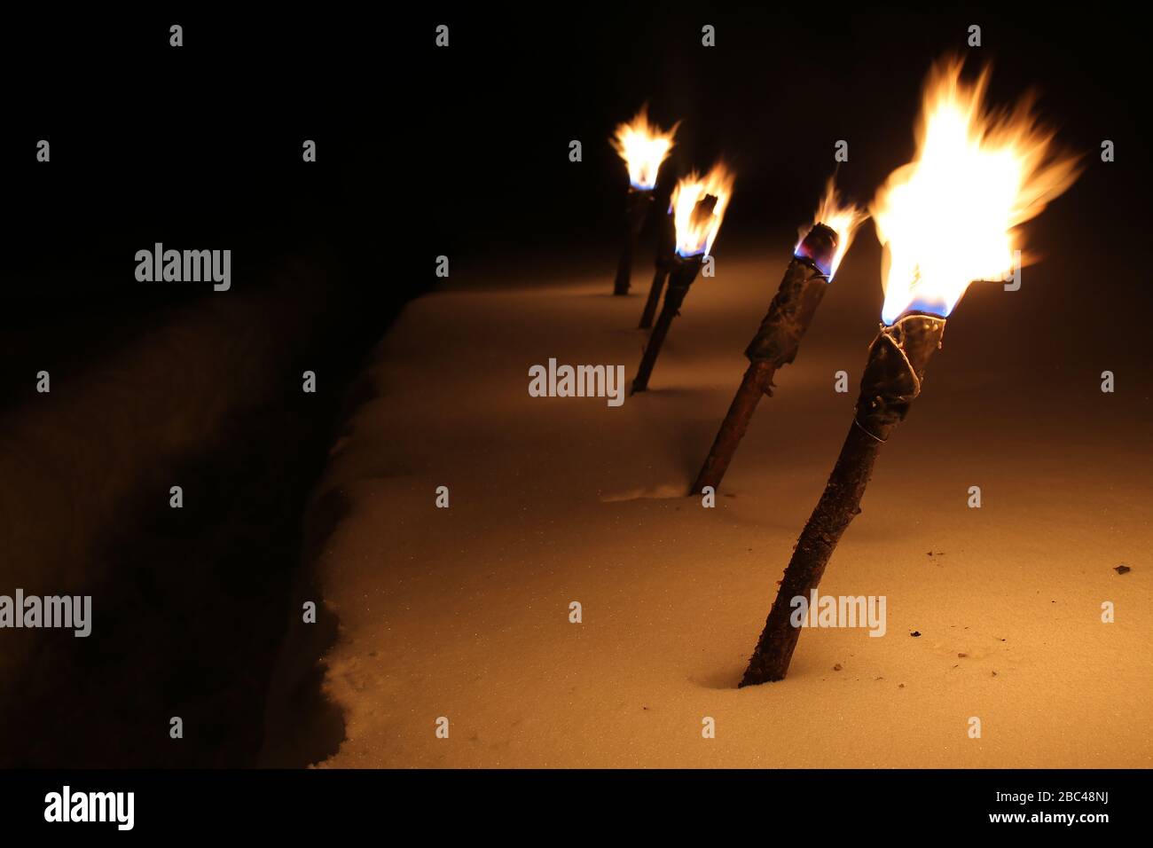 Row of burning torches in the snow. Stock Photo