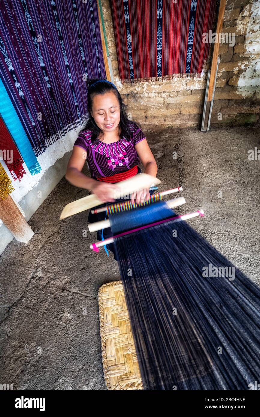 A young woman weaves in a cooperative in the village of San Juan on the shore of Lake Atitlan, Guatemala. Stock Photo