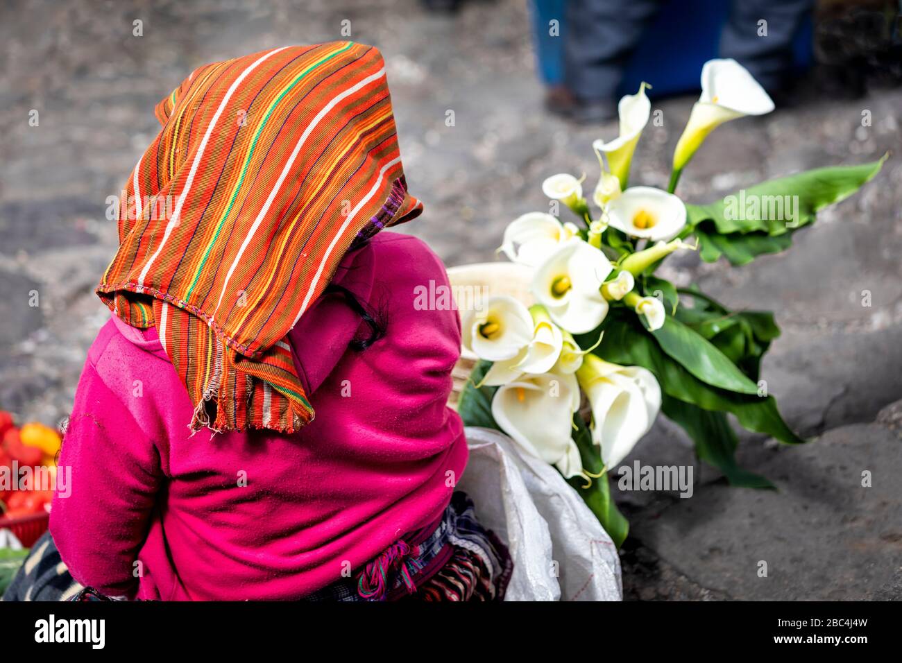 A woman sells calla lilies in the Chichicastenango, Guatemala market. Stock Photo