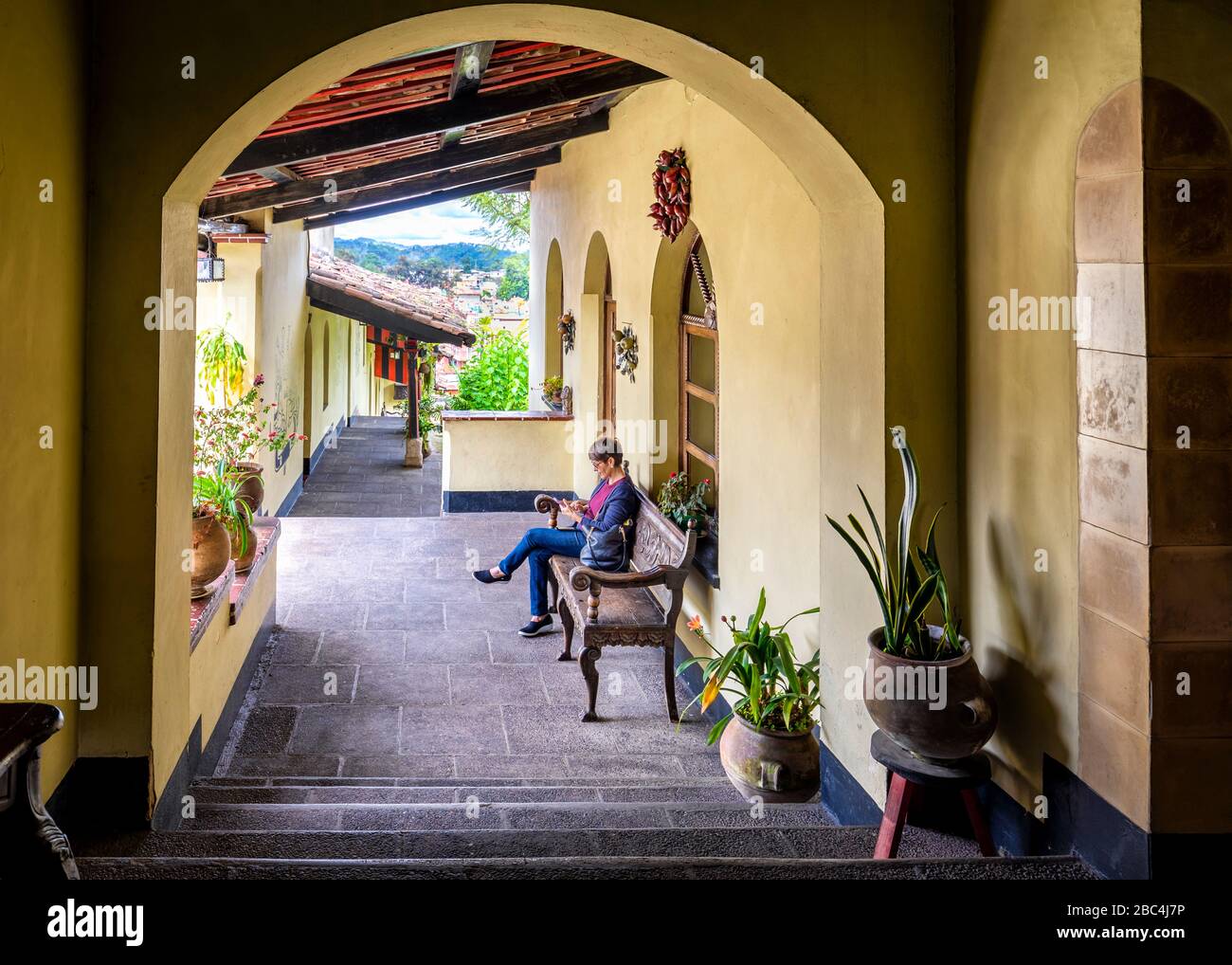 A tourist checks her phone at a colonial hotel in Guatemala. Stock Photo