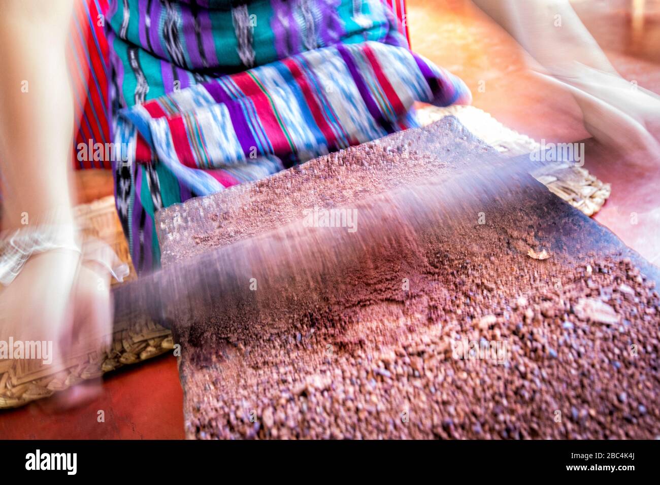 A young woman hand presses cacao beans into chocolate paste in the village of San Juan on the shore of Lake Atitlan, Guatemala. Stock Photo
