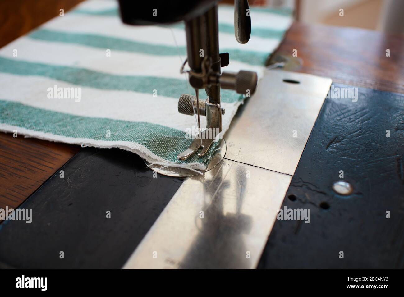 sewing a pleated cloth mask upcycled from a green and white striped dishtowel on an antique singer 127 sewing machine Stock Photo