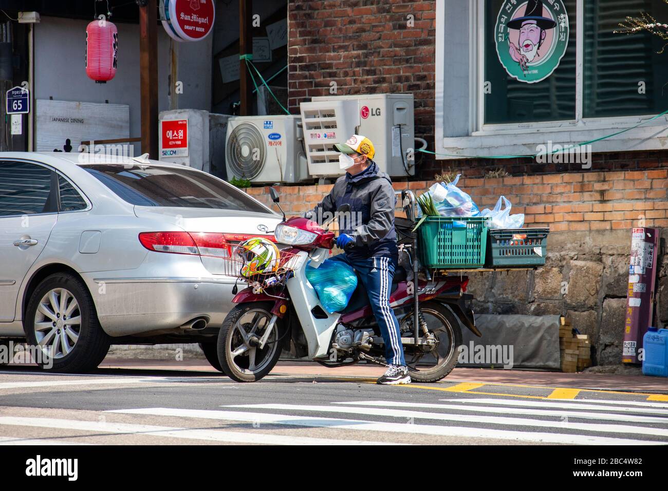 Motorcycle delivery wearing a mask during the Coronavirus pandemic, Seoul, South Korea Stock Photo