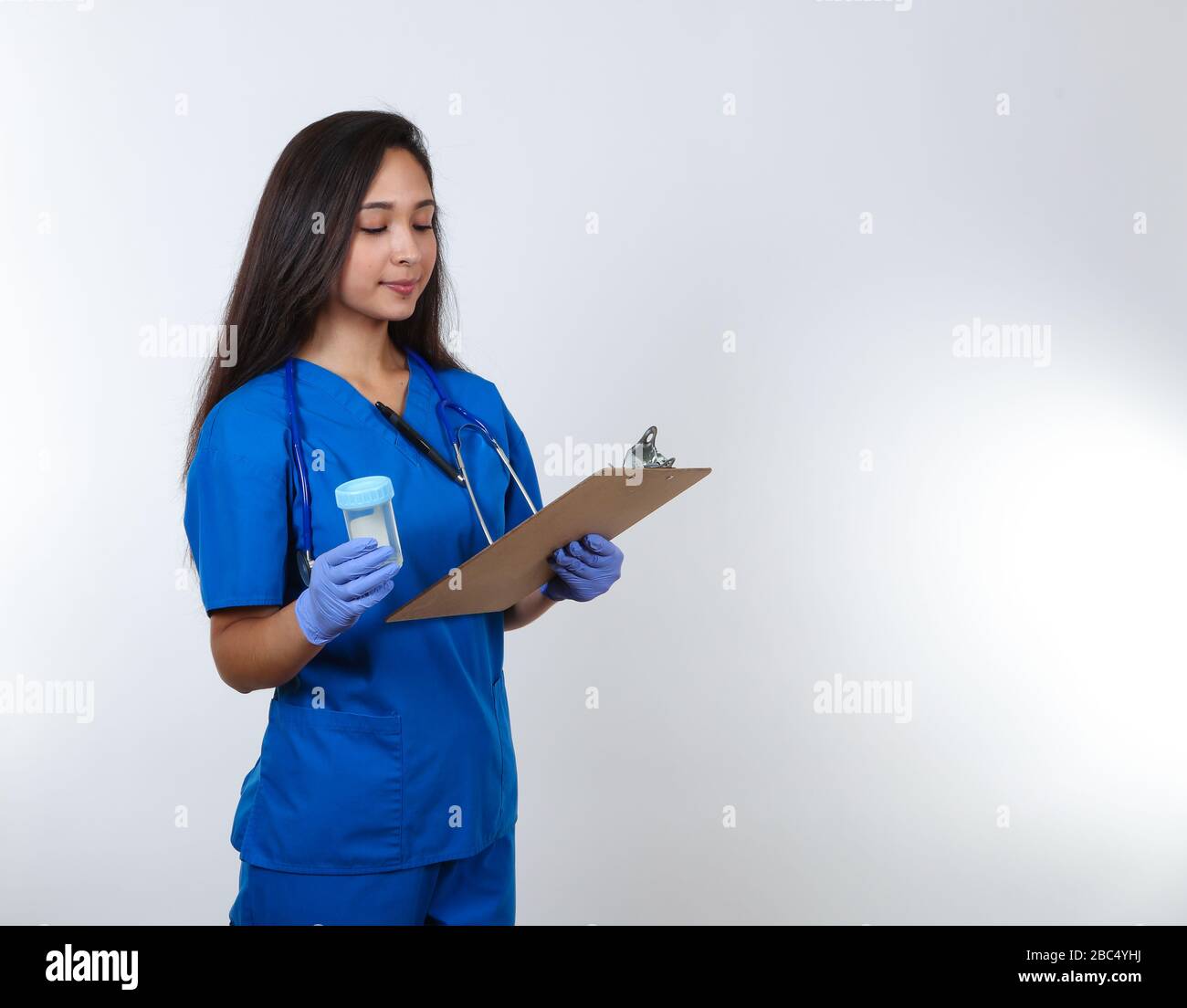A young female nurse in blue scrubs prepares to administer a drug test