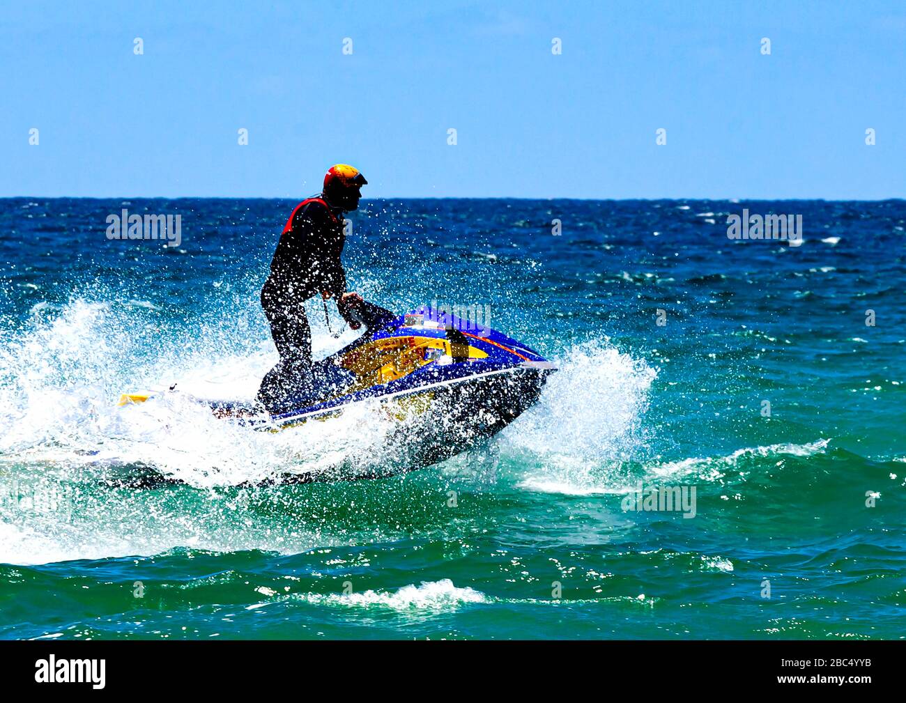 Lifesaver on water scooter splashing through waves at Merimbula on New South Wales south coast in Australia Stock Photo