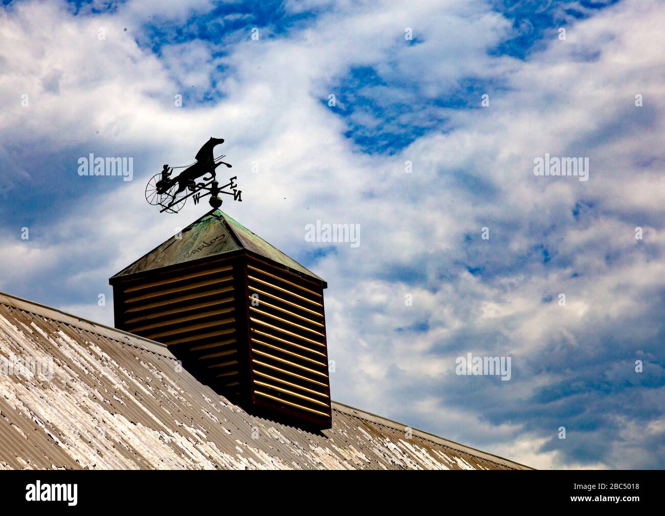 Trotting weather vane on hut with clouds in blue sky Stock Photo