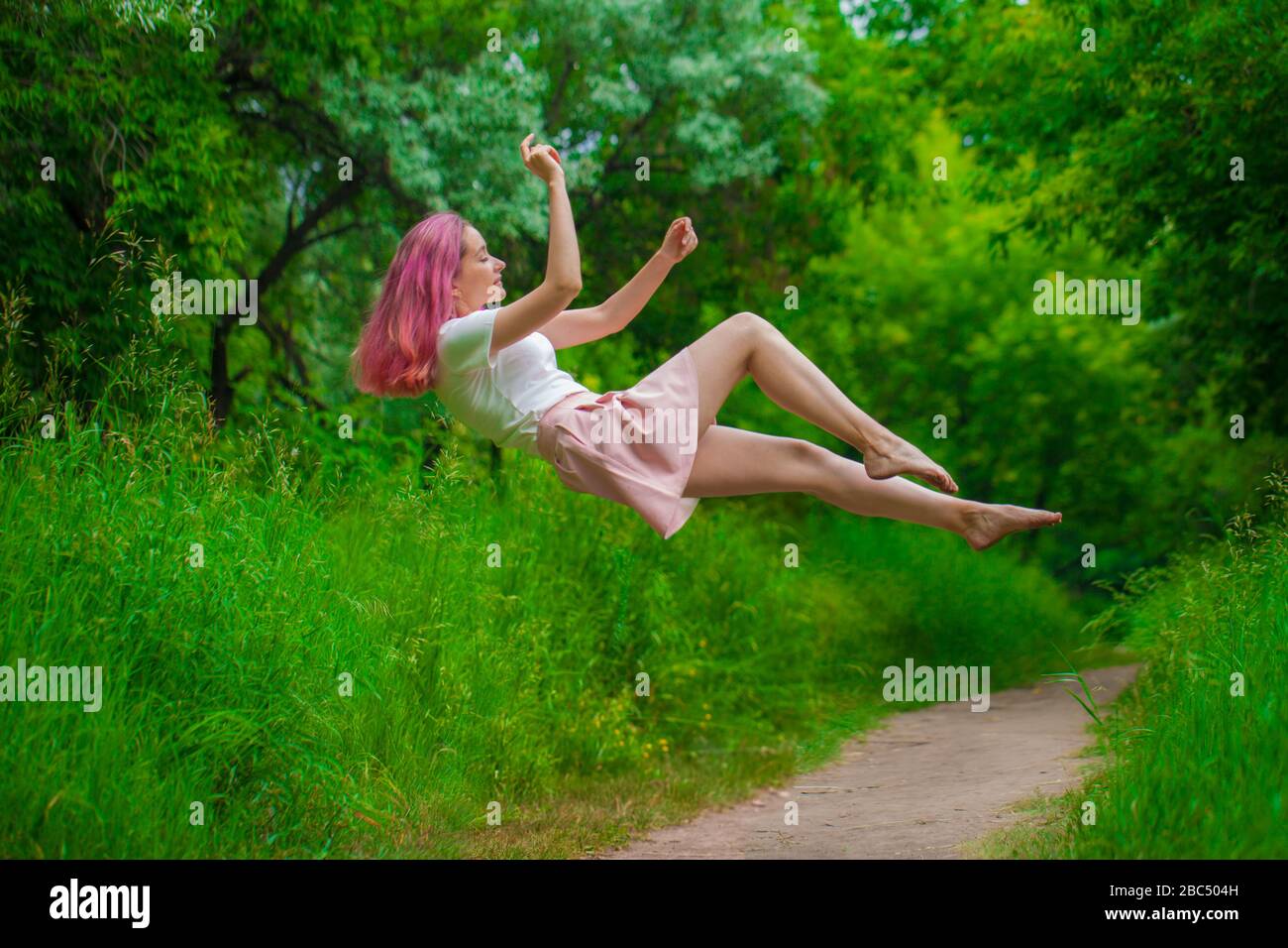 Hello Spring! Gorgeous girl with raspberry hair among deer and flowers. Spring dream. Girl flying. Levitation and weightlessness Stock Photo