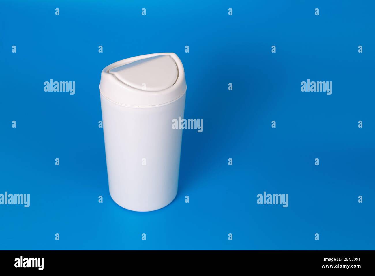 Small table white trash can on a blue background. Copy space. Stock Photo