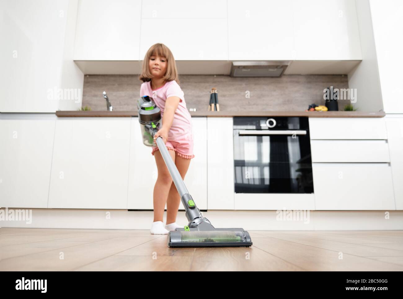 Little girl Using Vacuum Cleaner in Room. Vacuuming and Cleaning the