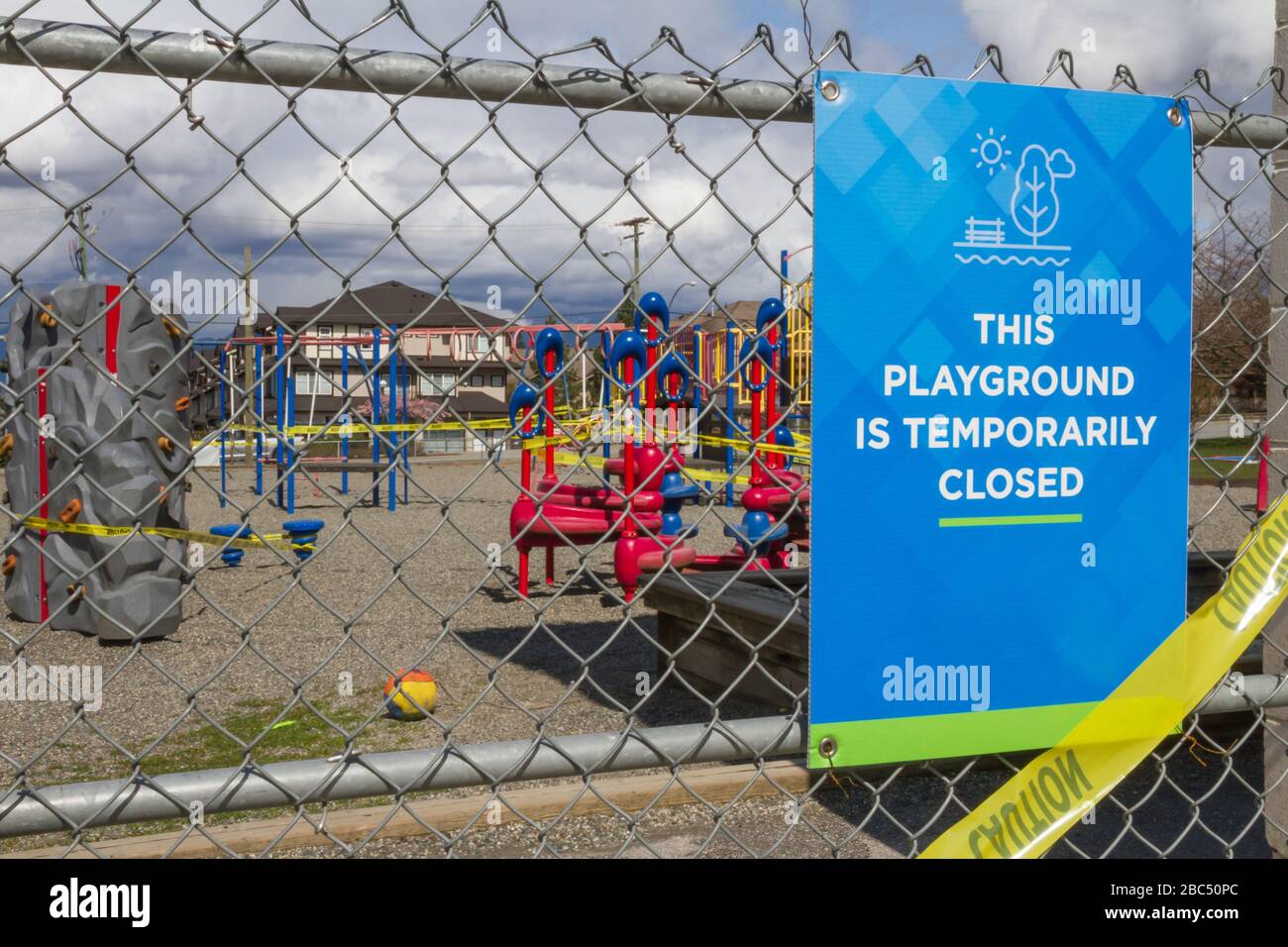 Playground is temporarily closed sign on chain link fence with playground in background Stock Photo