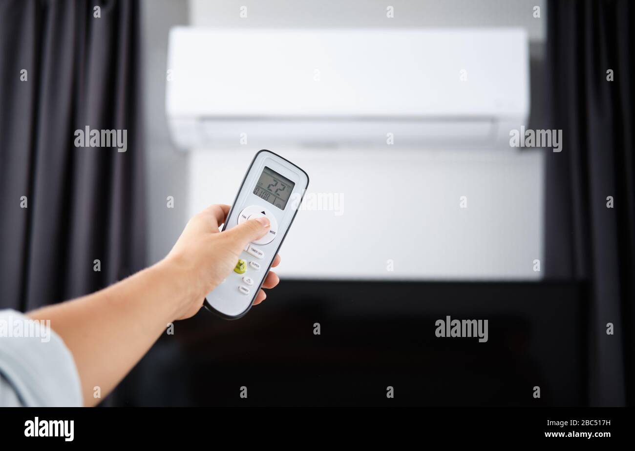 Hand with Remote control on off. Remote Control Directed on the Conditioner Stock Photo