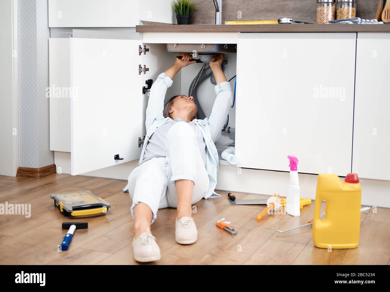 Woman fixing kitchen sink Stock Photo - Alamy
