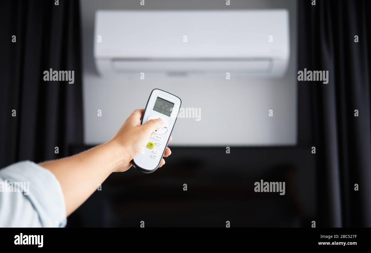 Hand with Remote control on off. Remote Control Directed on the Conditioner Stock Photo