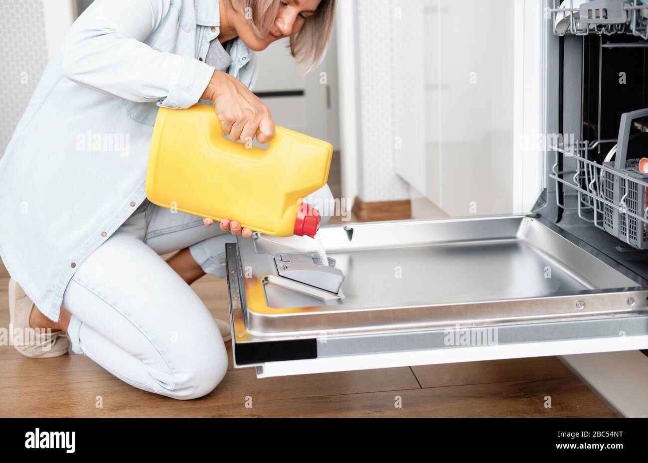 Woman Pour Powder in Dishwasher box. Dishwasher with Dirty Dishes. Washing dishes in the kitchen