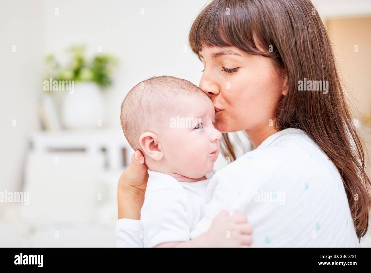Loving mother gives her baby a kiss on the forehead Stock Photo