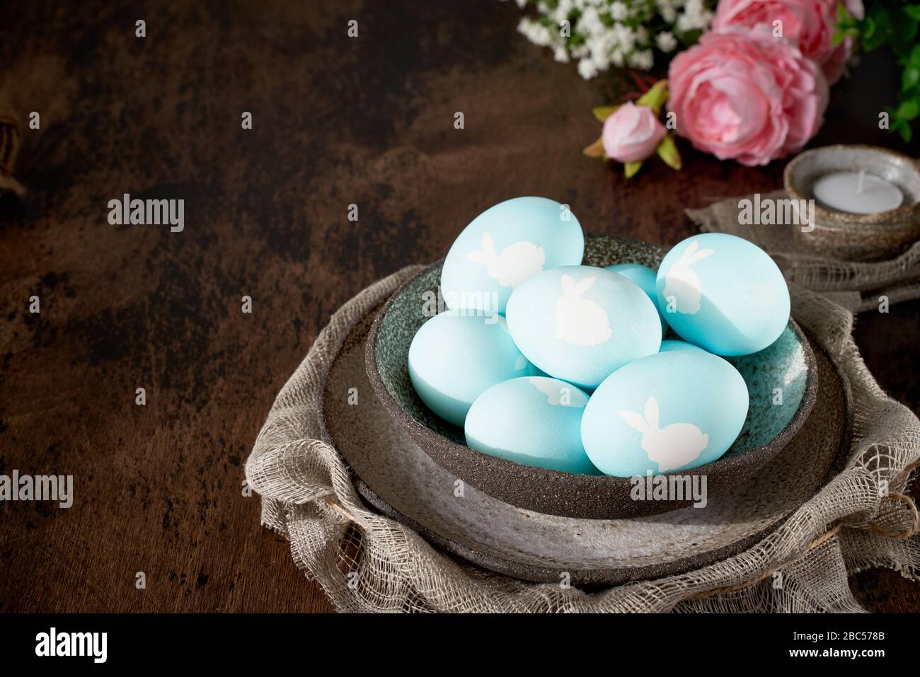 Unusual Easter on dark old background. Ceramic brown bowl with blue eggs. Stock Photo