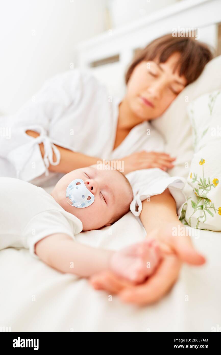 Mother and baby sleep together in bed at home Stock Photo