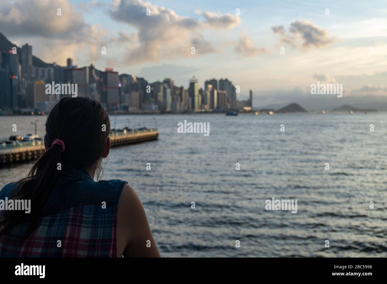 The girl on the pier looks at the sunset and cityscape Stock Photo - Alamy