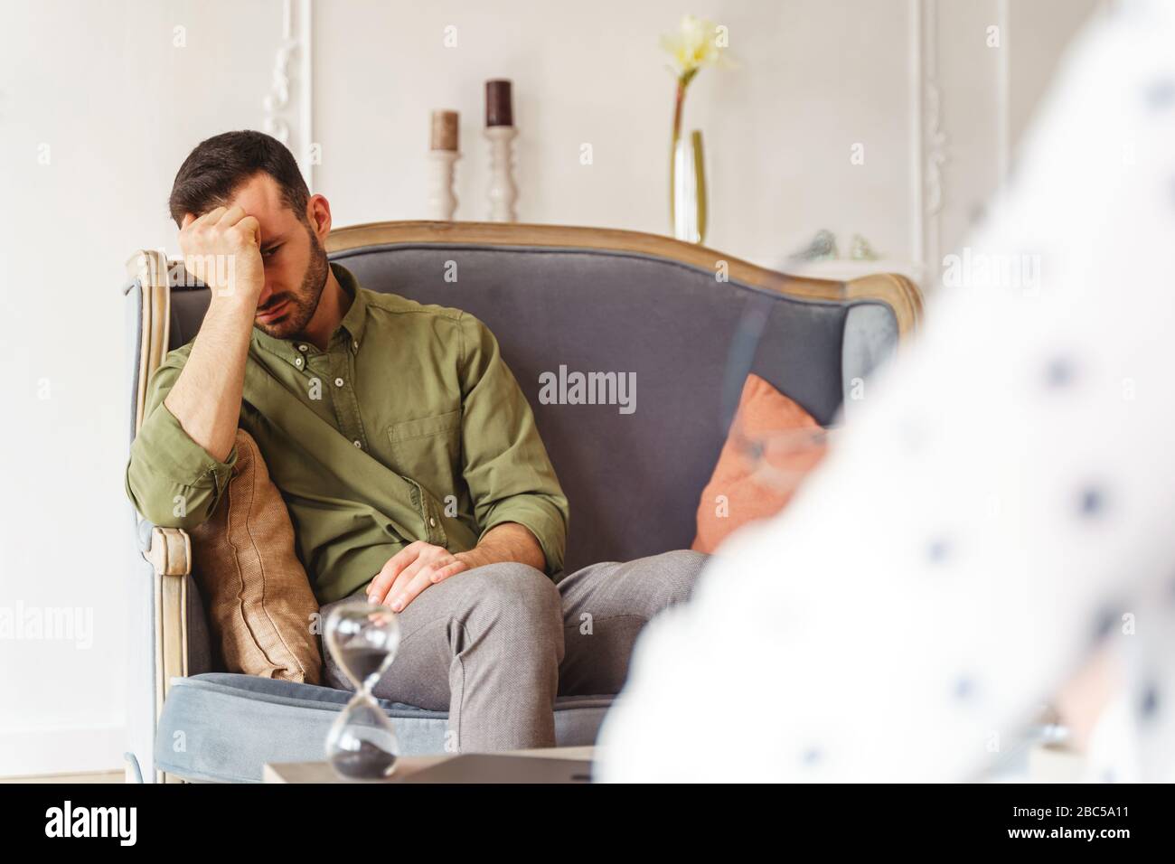 Low-spirited dark-haired male patient on a sofa Stock Photo