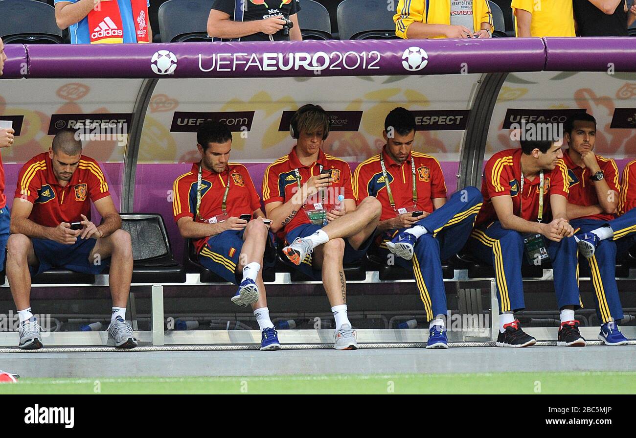 Members of the Spain squad including Juan Mata (second left) and Fernando Torres (third left) sit in the dugout before kick-off Stock Photo