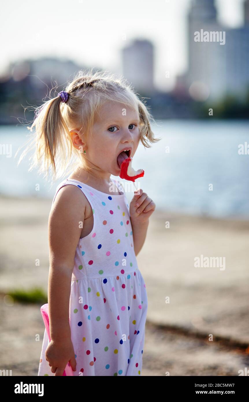 Little baby girl eating lollipop in the park Stock Photo