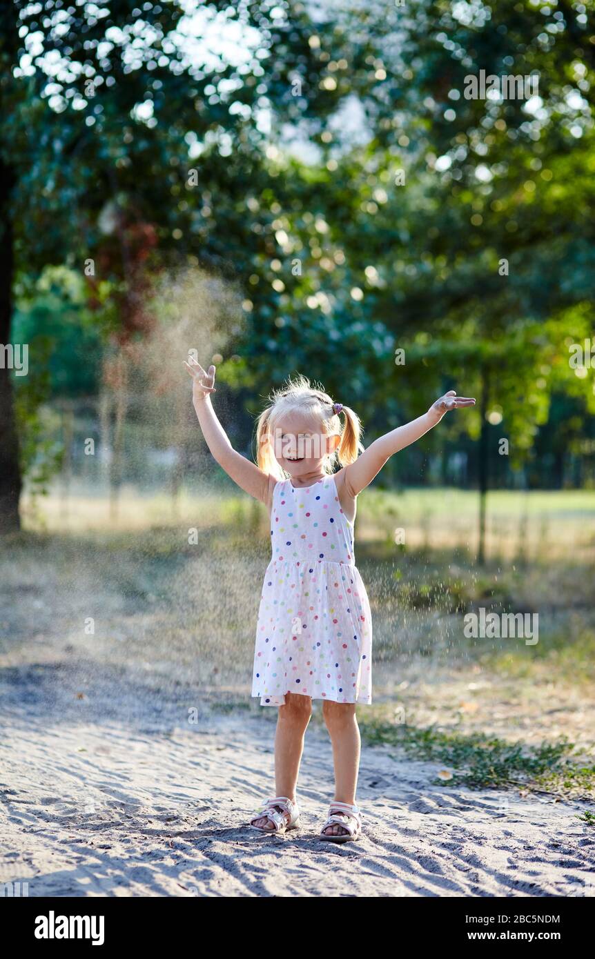 Adorable child in white dress posing outdoors.Girl having fun. Little baby girl in the park Stock Photo