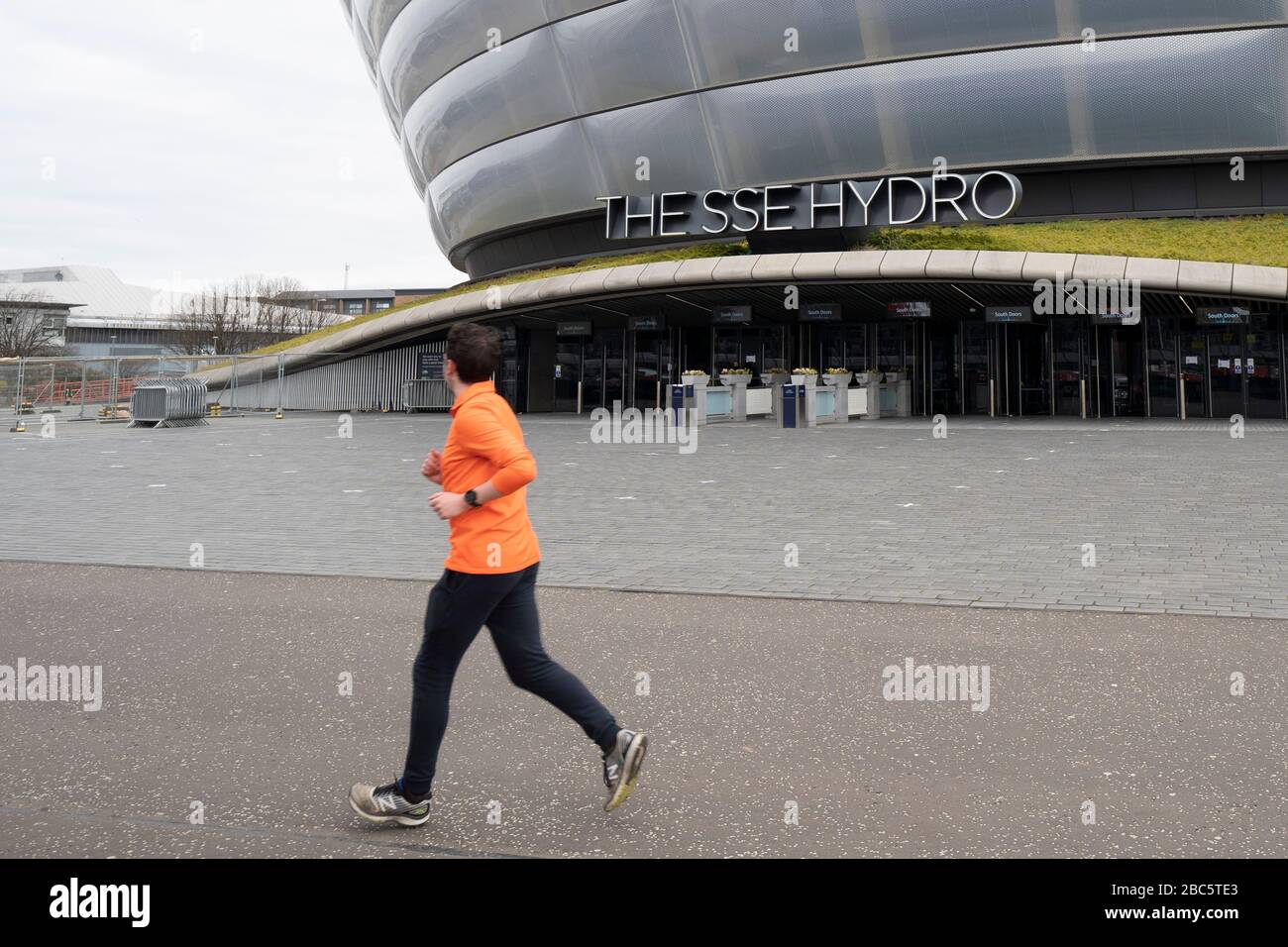 Glasgow, Scotland, UK. 3 April, 2020. Jogger runs  past SSE hydro during building of temporary  NHS Louisa Jordan field hospital at the Scottish Events Campus (SEC) in Glasgow.  Iain Masterton/Alamy Live News Stock Photo