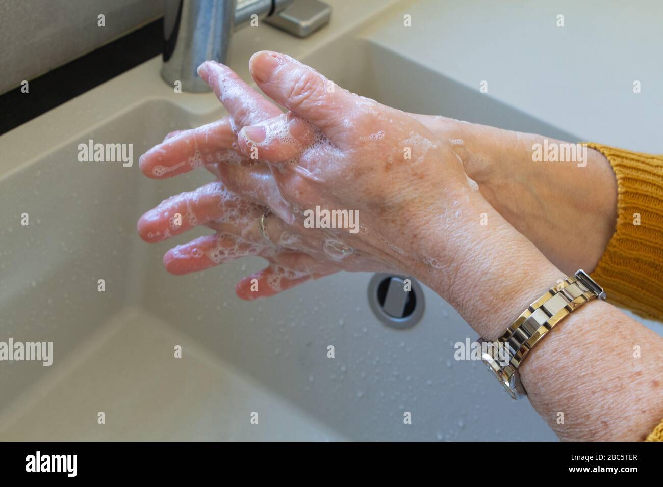 Woman washing her hands with soap in a bathroom Stock Photo - Alamy